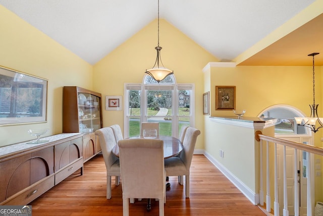 dining room featuring light wood-type flooring, lofted ceiling, and a chandelier