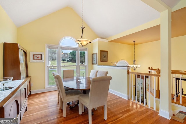 dining room with high vaulted ceiling, light wood-type flooring, and an inviting chandelier