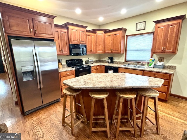 kitchen with black appliances, sink, a center island, and a breakfast bar area