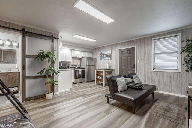 living room with wood walls, a barn door, and light hardwood / wood-style flooring