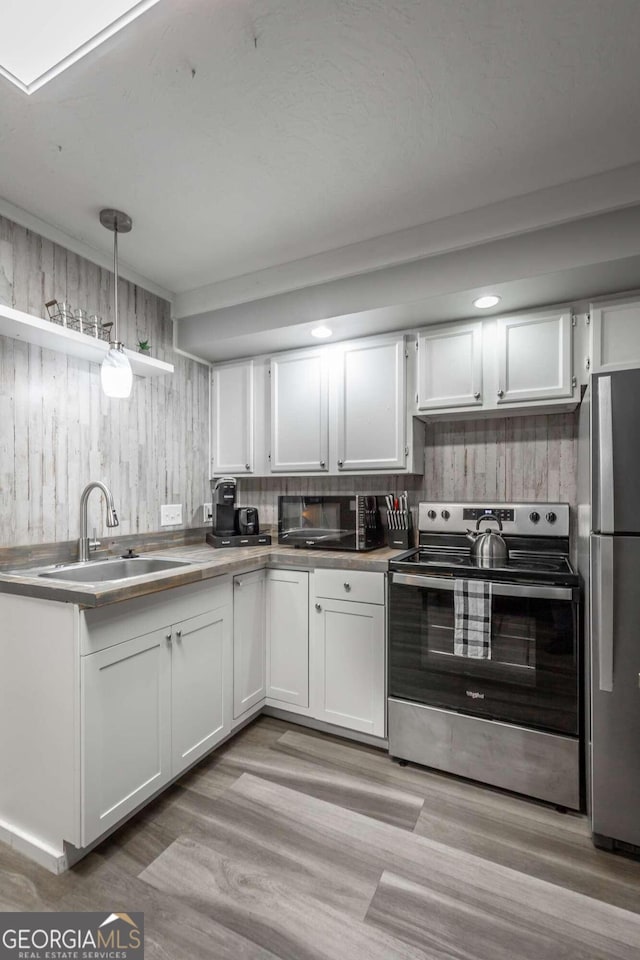 kitchen featuring decorative light fixtures, white cabinets, sink, and stainless steel appliances