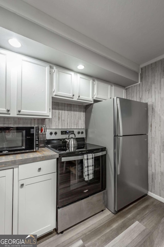 kitchen with stainless steel appliances, light hardwood / wood-style floors, white cabinetry, and decorative backsplash