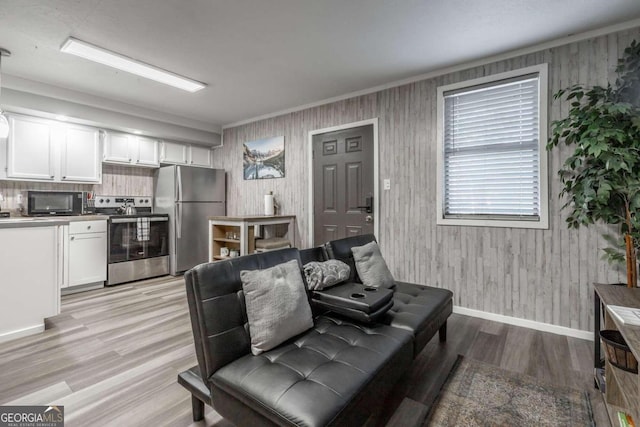 living room featuring light wood-style floors, baseboards, and ornamental molding