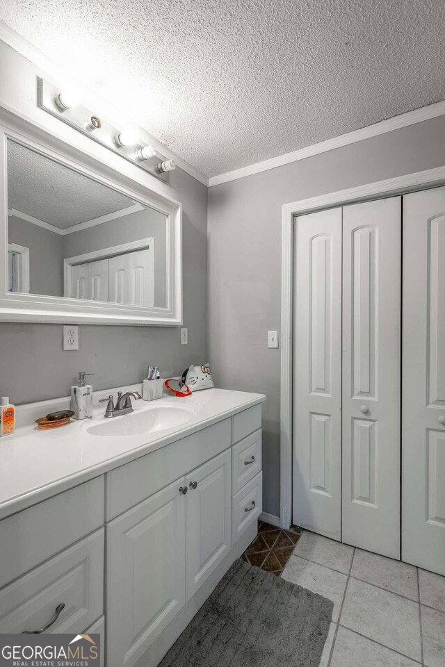 bathroom with ornamental molding, tile patterned flooring, vanity, and a textured ceiling