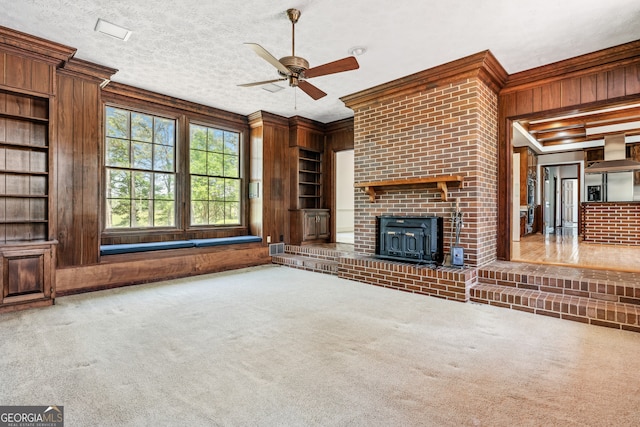 unfurnished living room with wooden walls, a textured ceiling, ornamental molding, and carpet floors