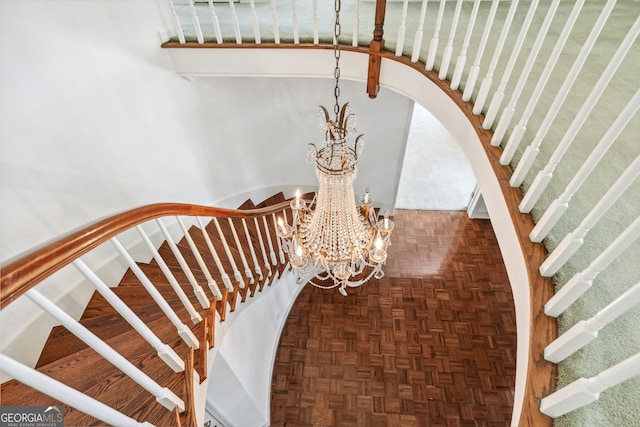 stairway with parquet flooring and a notable chandelier