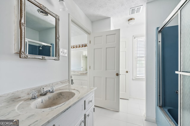 bathroom featuring bath / shower combo with glass door, vanity, tile patterned floors, and a textured ceiling