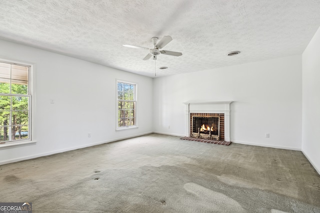 unfurnished living room featuring a fireplace, carpet floors, a textured ceiling, and ceiling fan