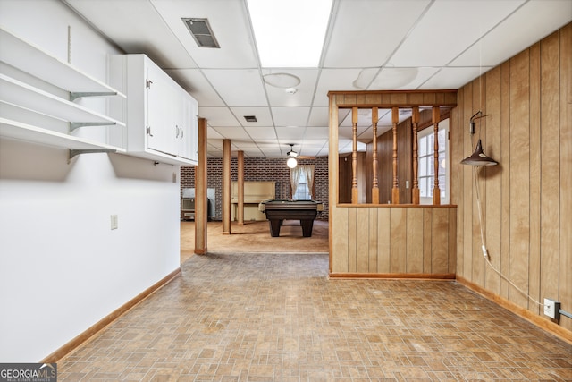 interior space with wood walls, white cabinetry, pool table, and a paneled ceiling