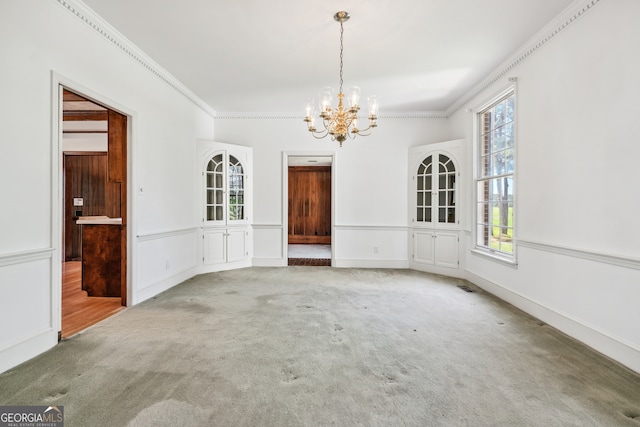 unfurnished dining area with carpet flooring, ornamental molding, and a notable chandelier