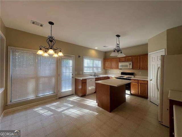 kitchen with a center island, a chandelier, sink, white appliances, and decorative light fixtures