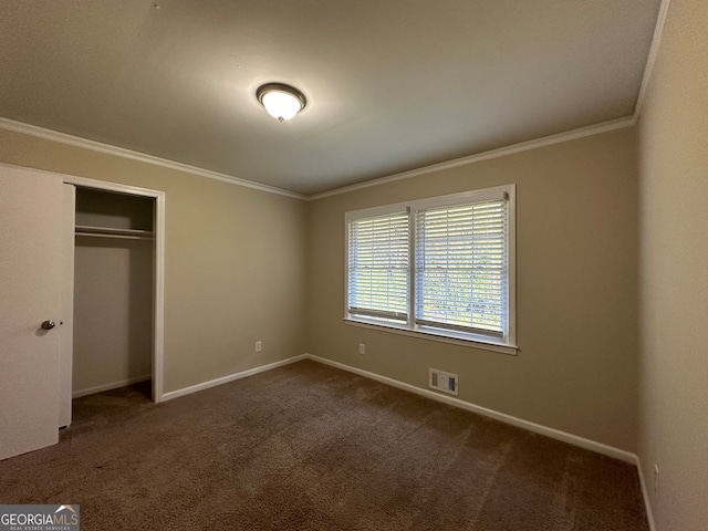 unfurnished bedroom with a closet, dark carpet, and crown molding