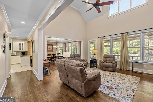 living room featuring a high ceiling, hardwood / wood-style flooring, ornamental molding, and ceiling fan with notable chandelier