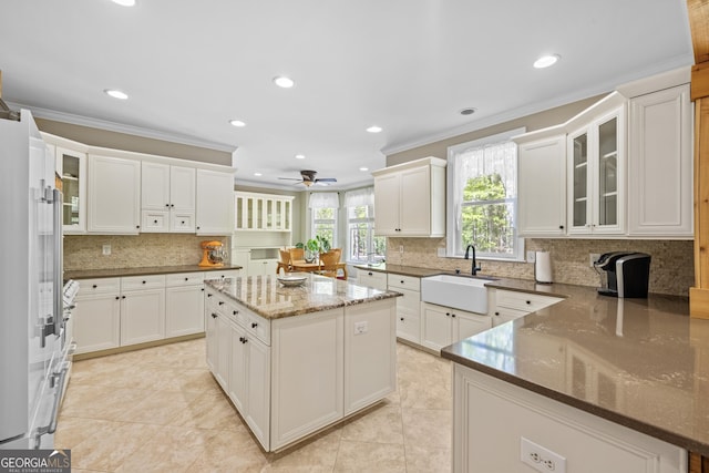 kitchen with white cabinets, sink, a kitchen island, and ornamental molding