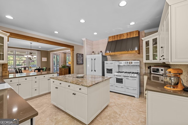 kitchen with a kitchen island, white cabinetry, white appliances, and an inviting chandelier