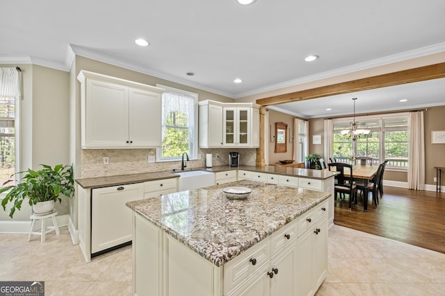 kitchen with a wealth of natural light, decorative light fixtures, crown molding, and a center island