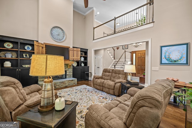 living room featuring dark wood-type flooring, a towering ceiling, and crown molding