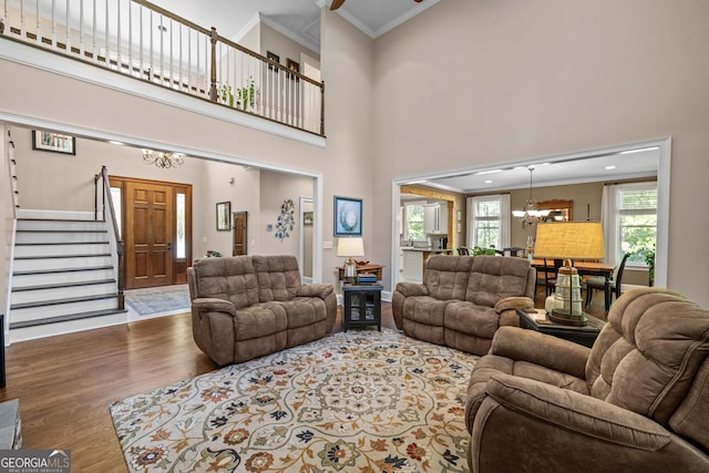 living room featuring ornamental molding, hardwood / wood-style floors, a towering ceiling, and a notable chandelier