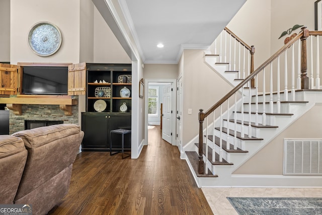 entryway with a stone fireplace, dark hardwood / wood-style floors, and crown molding