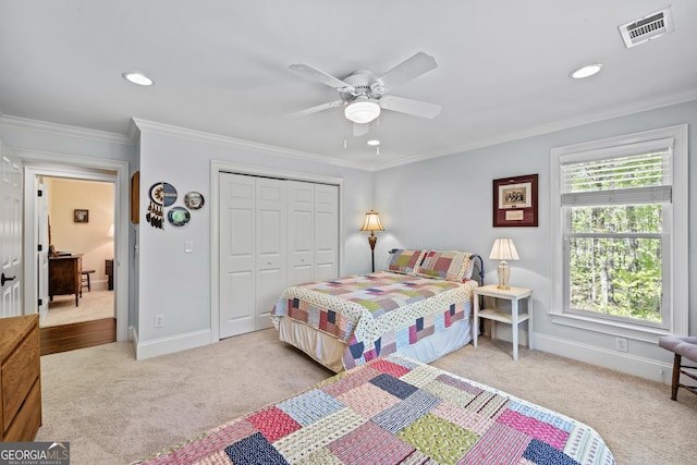 carpeted bedroom featuring ornamental molding, a closet, and ceiling fan