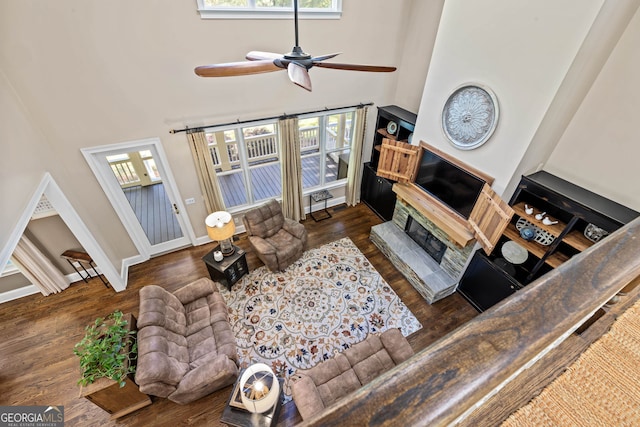 living room with ceiling fan, a towering ceiling, and dark hardwood / wood-style floors