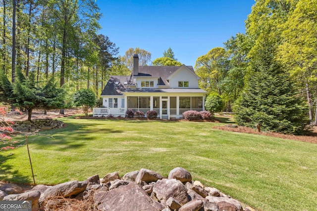 back of house featuring a lawn and a sunroom