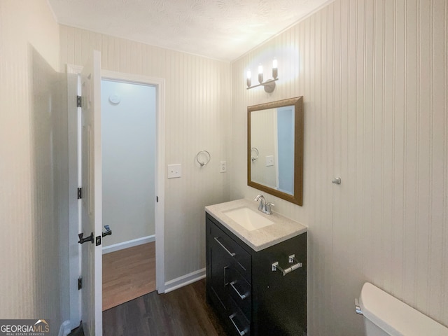 bathroom with a textured ceiling, vanity, hardwood / wood-style flooring, and toilet