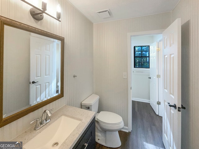 bathroom featuring toilet, vanity, and hardwood / wood-style floors