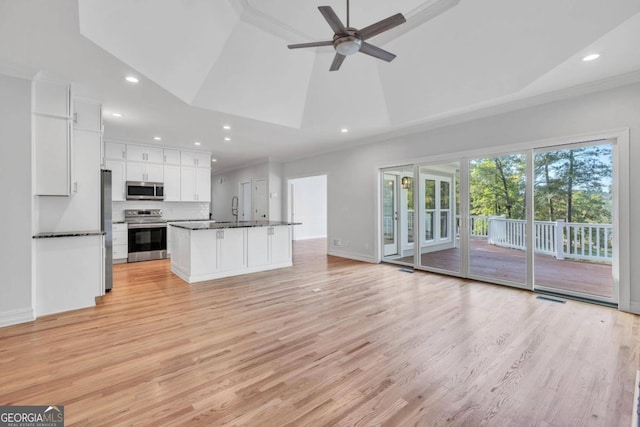 kitchen featuring white cabinets, light hardwood / wood-style floors, stainless steel appliances, and a center island with sink