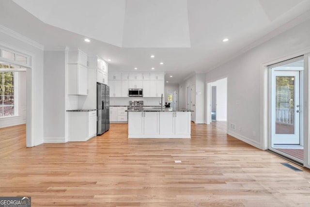 kitchen featuring white cabinets, a kitchen island with sink, light wood-type flooring, and appliances with stainless steel finishes