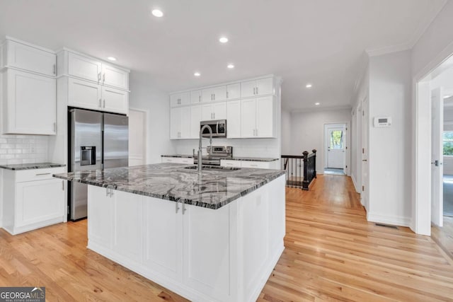 kitchen featuring stainless steel appliances, white cabinetry, and light hardwood / wood-style flooring