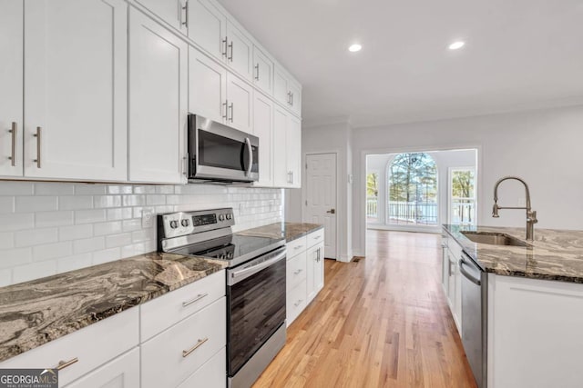 kitchen featuring white cabinetry, stainless steel appliances, sink, and dark stone countertops