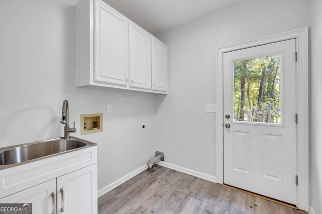 clothes washing area with hookup for an electric dryer, cabinets, sink, washer hookup, and light wood-type flooring