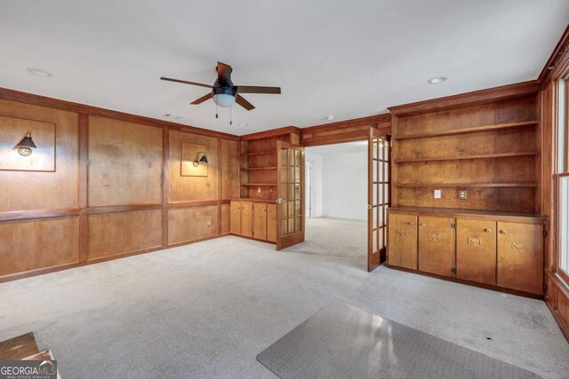 spare room featuring wood walls, light colored carpet, and ceiling fan