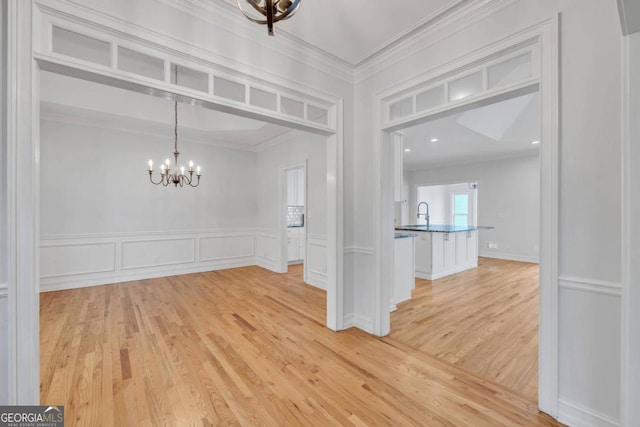 empty room with light hardwood / wood-style floors, a chandelier, and crown molding