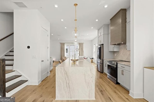 kitchen featuring a kitchen island, appliances with stainless steel finishes, light hardwood / wood-style floors, and hanging light fixtures