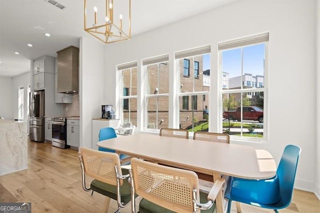 dining space featuring a notable chandelier, a healthy amount of sunlight, and light hardwood / wood-style flooring