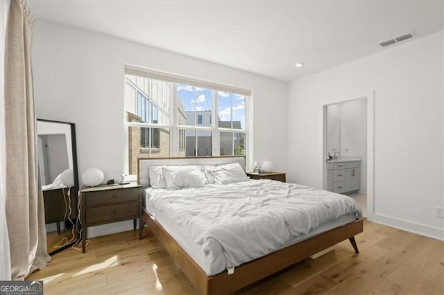 bedroom featuring light wood-type flooring and ensuite bath