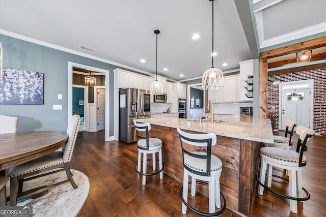 kitchen featuring white cabinetry, sink, appliances with stainless steel finishes, hanging light fixtures, and dark hardwood / wood-style flooring