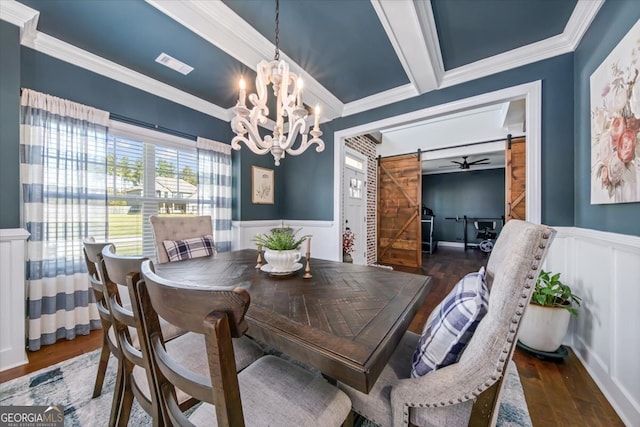 dining room with a barn door, ceiling fan with notable chandelier, crown molding, and dark hardwood / wood-style flooring