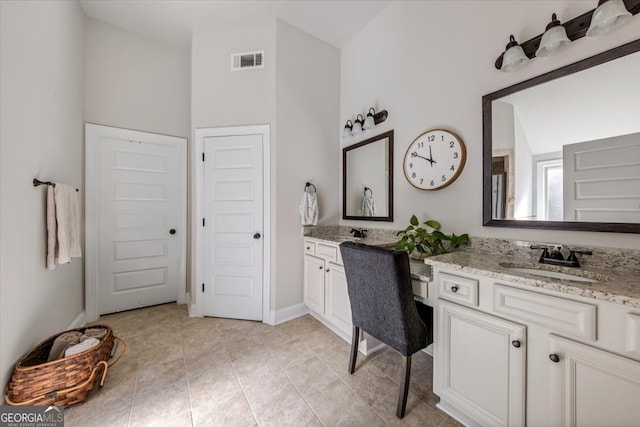 bathroom with a towering ceiling, vanity, and tile patterned floors