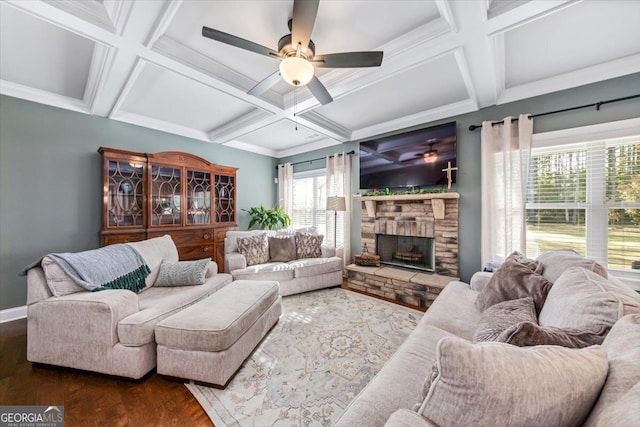 living room featuring dark wood-type flooring, coffered ceiling, a stone fireplace, and ceiling fan