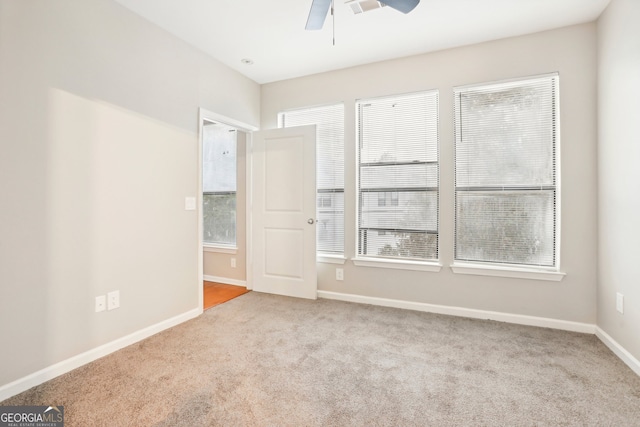 empty room featuring light carpet, a healthy amount of sunlight, and ceiling fan