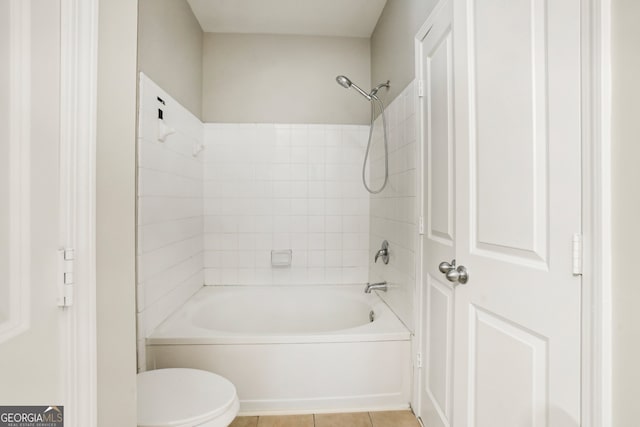 bathroom with toilet, tiled shower / bath combo, and tile patterned floors