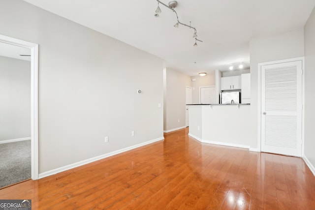 unfurnished living room featuring wood-type flooring and track lighting