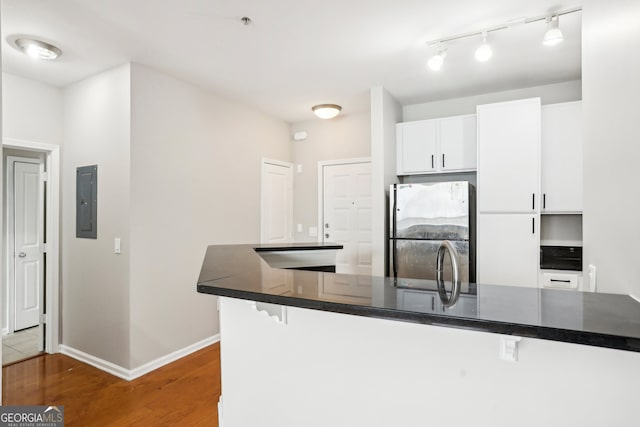 kitchen with kitchen peninsula, a kitchen breakfast bar, dark hardwood / wood-style floors, white cabinetry, and stainless steel fridge