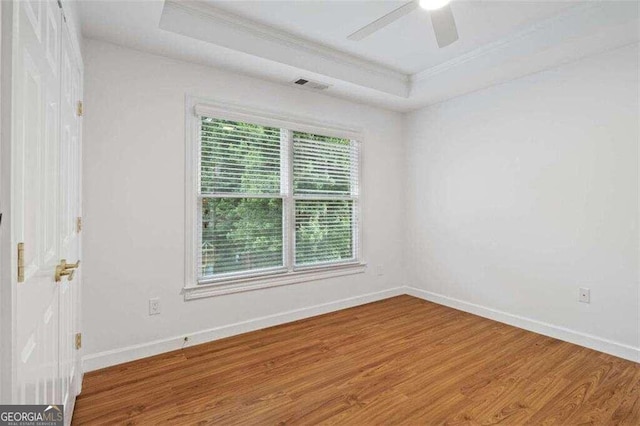 spare room featuring a wealth of natural light, hardwood / wood-style floors, crown molding, and a raised ceiling