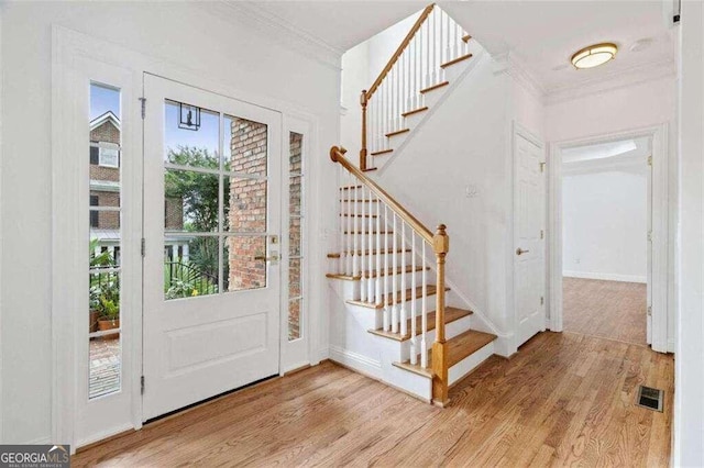 foyer entrance with light wood-type flooring and crown molding