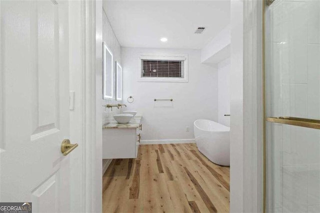 bathroom with vanity, hardwood / wood-style floors, and a bathing tub