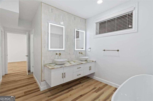 bathroom featuring hardwood / wood-style floors, a tub to relax in, and vanity